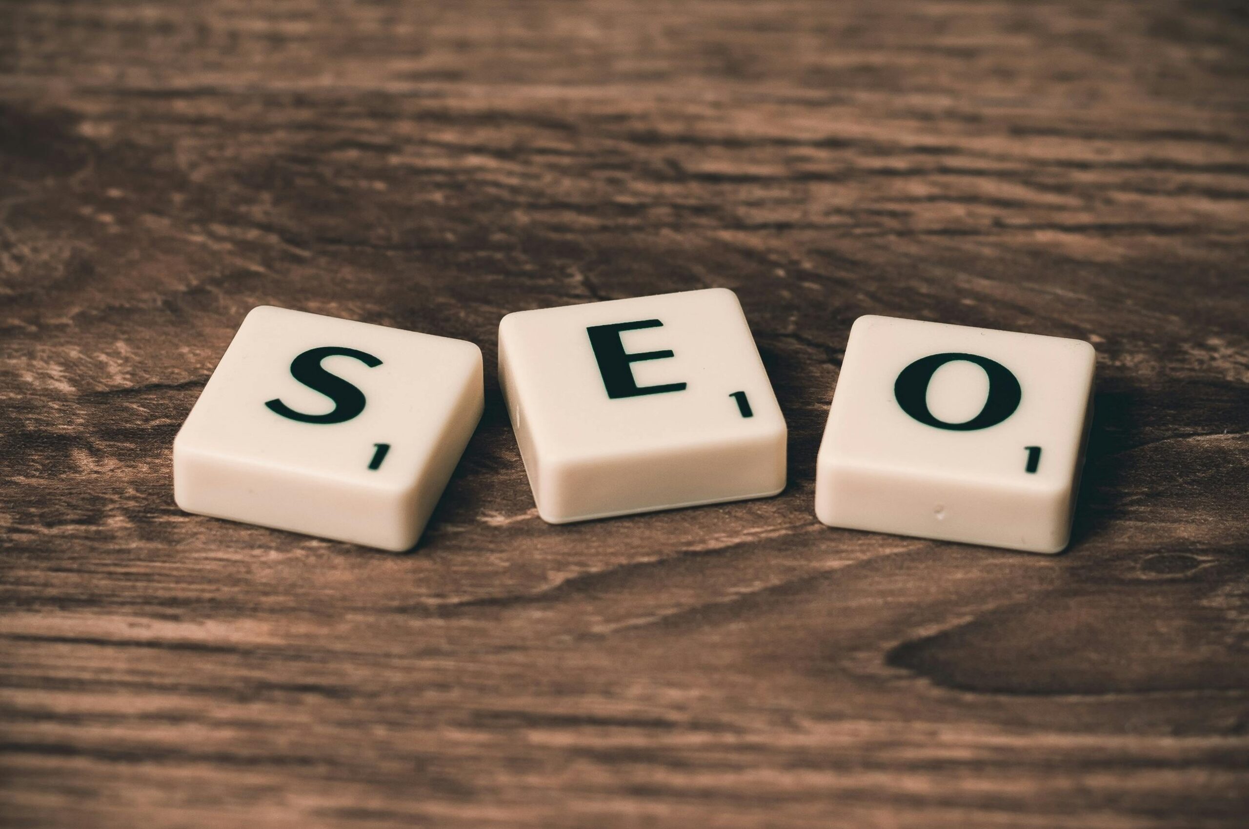 SEO concept displayed using scrabble tiles on a wooden background, representing website search engine optimization.